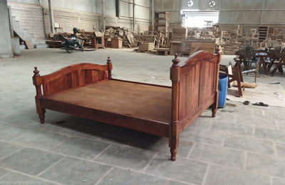 Solid Sheesham wood bed frame with turned posts, angled workshop view