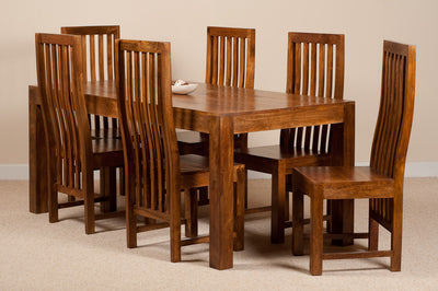 A 7-piece wooden dining set consisting of a rectangular table and six matching slatted-back chairs, shown in a warm medium-brown finish against a neutral beige wall and carpet.