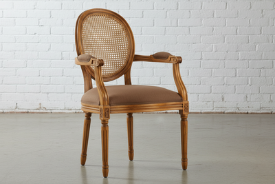 Wooden armchair with brown cushion against a white brick wall.