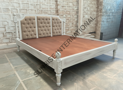 Solid wood bed with carved details and tufted upholstered headboard, angled view