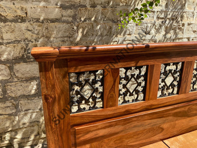 Sheesham wood bed headboard with black powder-coated artistic jali panels, close-up