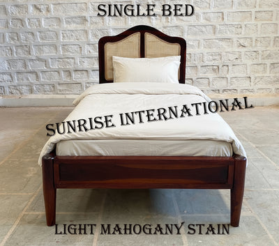 Single bed with light mahogany stain headboard and bedding against a brick wall.