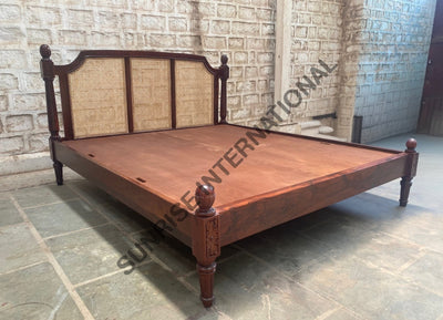 Solid wooden bed with rattan cane headboard, angled workshop view