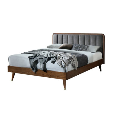 Solid wood bed with grey upholstered headboard and metal-capped legs, bedroom view