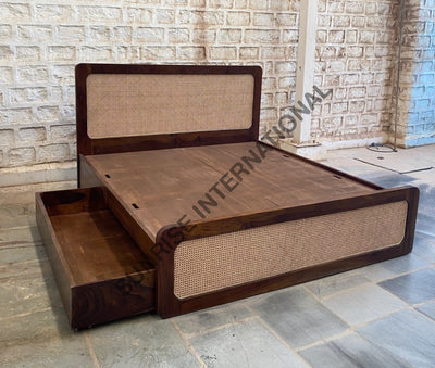 Wooden bed with rattan cane headboard and side storage drawer, angled view