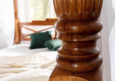 Hand-carved Mango wood bed post detail on four poster bed