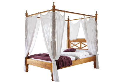 Wooden canopy bed with carved Mango wood posts and white curtains, angled view
