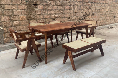 Angled view of wooden dining table set with rattan cane seating and bench